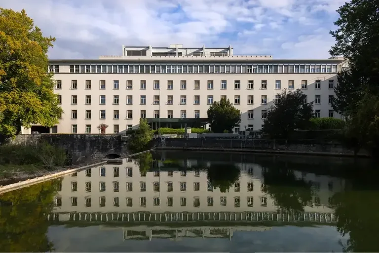 Hauptgebäude des Vitus-Areal Winterthur, frontal aufgenommen mit klarer Spiegelung im Wasser und umgebender Grünanlage.