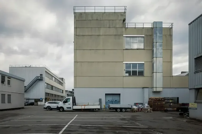 Industriegebäude im Vitus-Areal Winterthur mit Anlieferungsbereich, Fahrzeugen und Lagergut auf dem Vorplatz.